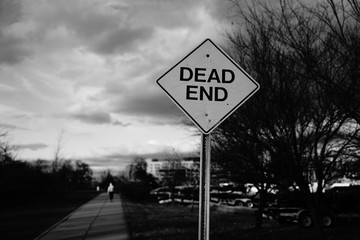 Sign dead end with a man going away behind it b&w