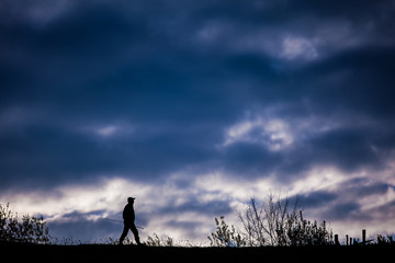 Shepherd walking silhouette carrying a rod