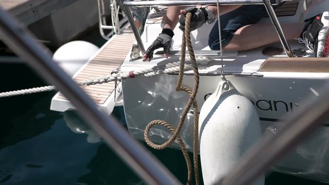 Sailor inties rope on handling appliance. Hands pulling ropes, winding sheets around winches close-up. Sailor's hand on a winch of sailing boat. Sailing.