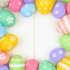 Colorful pastel Easter Egg square frame against a white wood background. Top view with copy space.
