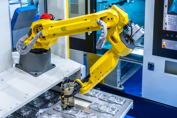 The robot arm. Manipulator puts the parts in the machine..Robotic technology. Automation of production. Industrial work of the robot manipulator. Robots in production.