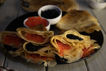 Pancakes stuffed with black caviar close-up, mix