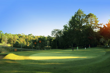 The evening golf course has sunlight shining down at golf course in Thailand