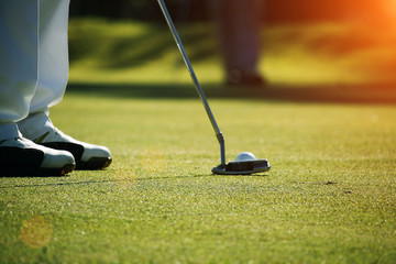 Golfer putting golf ball on the green golf