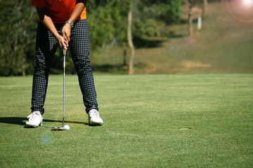 Golfer putting golf ball on the green golf