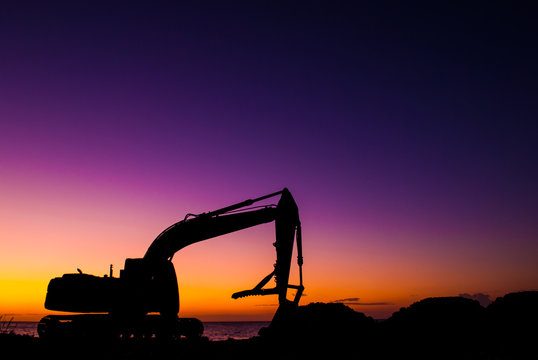 An industrial construction vehicle has been silhouetted against the rising sun. The significance shows the dawn on the new beginning that development can bring