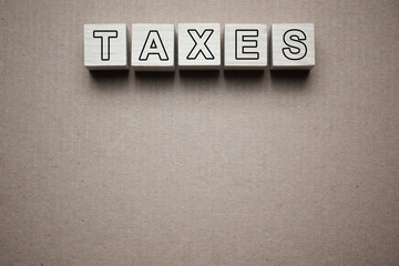 Taxes text written on wooden blocks isolated on piece of grey paper