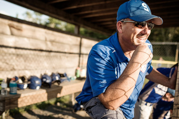 Baseball team coach watching match smiling 