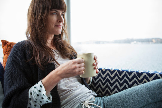 Mid adult woman sitting on sofa and drinking tea 