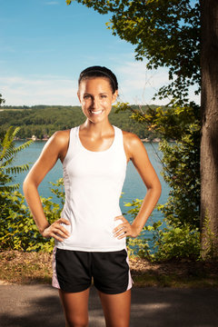 Woman wearing workout gear smiling by lake 