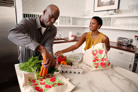 Couple Unpacking Shopping In Domestic Kitchen 