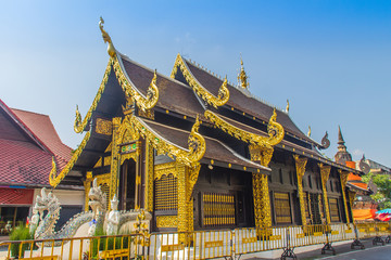 Fototapeta premium Beautiful golden Buddhist church in Lanna style architecture at Wat Inthakin Sadue Muang, Chiang Mai, Thailand. Wat Inthakin is the Buddhist temple where the Chiang Mai city pillar was placed in 1296.
