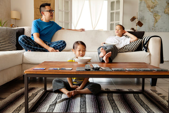Father sitting in living room on sofa with children (4-5, 6-7) 