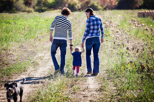Couple walking on meadow with their baby daughter (6-11 months) 
