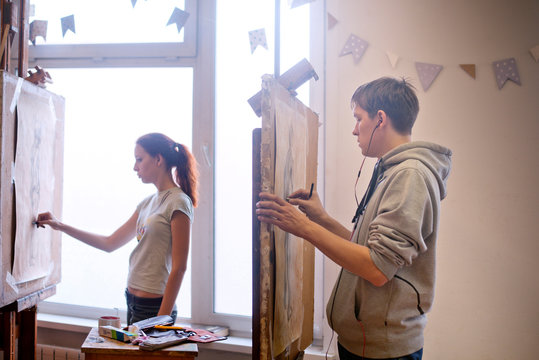 Two art students drawing live model 