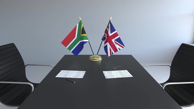 Flags of South Africa and the United Kingdom and papers on the table. Negotiations and signing an international agreement. Conceptual 3D animation