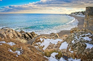 Snowy and rocky overlook of the ocean and beach during winter