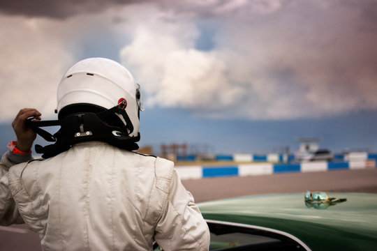 Race car driver putting helmet on 