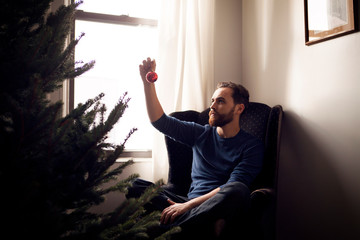 Young man hanging christmas ornament 