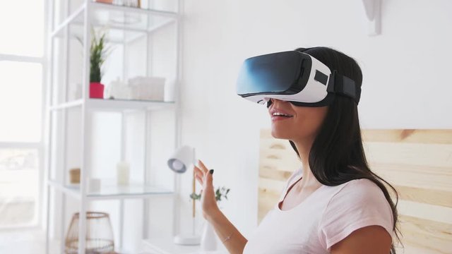 Portrait of smiling happy young woman getting experience using VR glasses at home