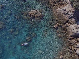 Aerial view of the ocean coast, rocks and surfer