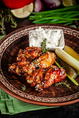 Fried glazed chicken wings in soy sauce and sesame. Cheese white sousa. Marinated vegetables on a ceramic plate. Background image. copy space