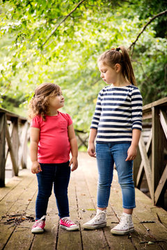 Girls (2-3, 6-7) face to face on footbridge 