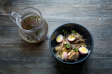 top view closeup noodles with shiitake mushrooms, eggs, wheat sprouts and pitcher with broth