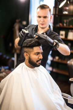 Barber splashes of spray on the client's hair. Haircut in the salon