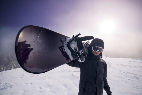 Portrait of man carrying on shoulder snowboard  