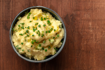 Pomme puree, mashed potatoes with scallions and thyme, shot from the top on a dark rustic background with a place for text