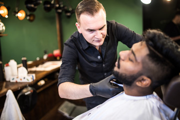 Close up. Young Man with beard client in barbershop hairdresser Barber on shaving electric razor