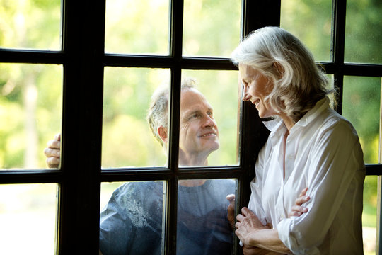 Mature couple looking at each other through window 