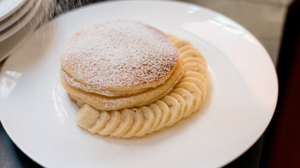 Pancakes on a white plate with sliced bananas