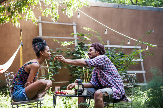 Couple in garden together eating strawberries 