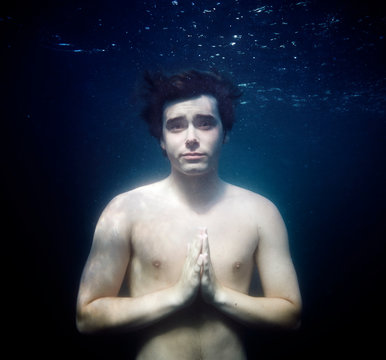 USA, Massachusetts, Magnolia, Young man praying underwater                               