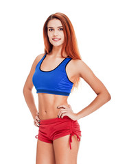 Obraz premium Smiling red-haired sporty woman with perfect body posing on white background