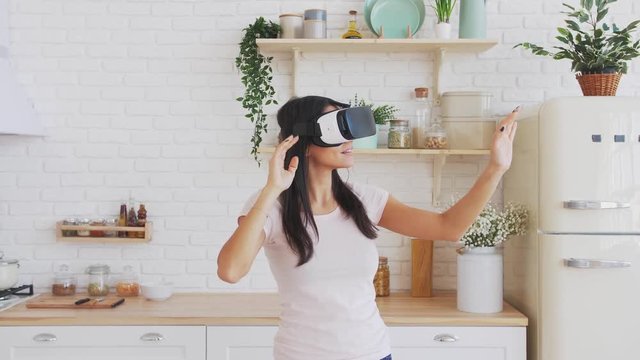 Young woman in VR glasses in kitchen at home