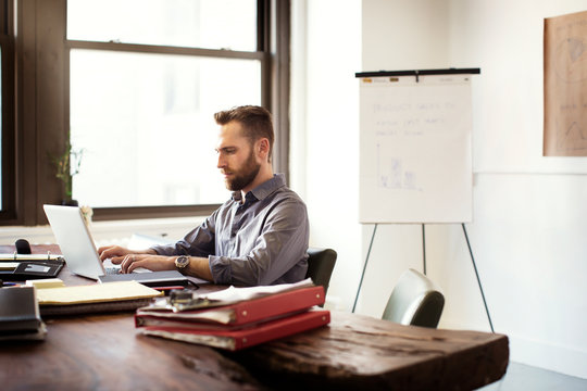 Man working with laptop at wooden table 