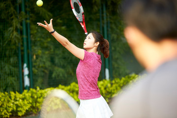 young asian tennis player practicing serve