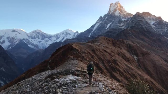 Hiker trakking to Mardi Himal basecamp. Machapuchare mountain peak in the distance. Himalayan mountains in Nepal