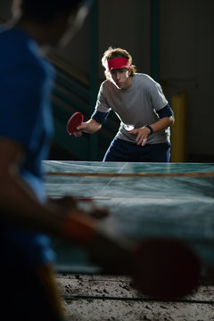 Two men playing table tennis at night 