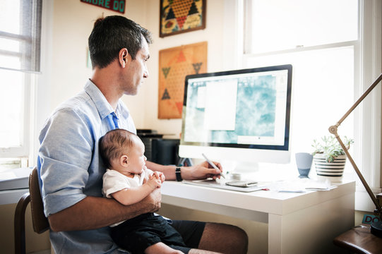 Father sitting with his baby son (2-5 months) at desk 