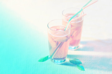 two glasses of refreshing pink drink with pieces of fruit. side view