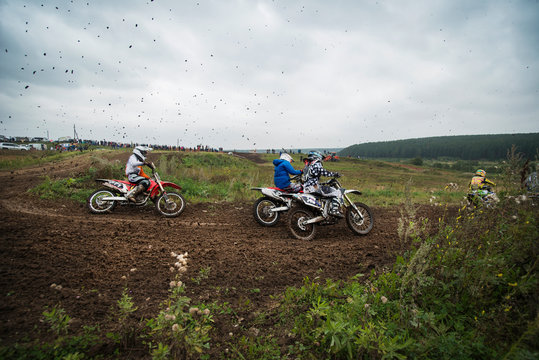 Group of motocross riders on dirt road 