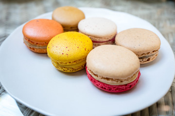 Colorful macaroon in variety taste on white round plate.