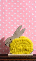 Yellow easter bunny in front of wall of points in a room. Bunny decoration and green wallpaper background on dots.