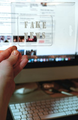 Fake news text and website on the background. Fake news conception with transparent words.