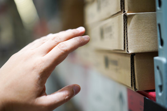 Close Up The Man Who Reaches His Hand To Furniture In A Brown Paper Box On Shelf In The Warehouse.