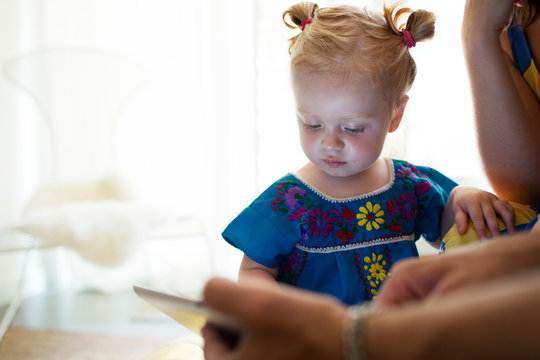 Baby girl (18-23 months) looking at digital tablet